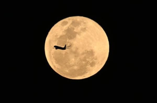 An aircraft flying past the harvest supermoon as it rose in Brisbane on Wednesday